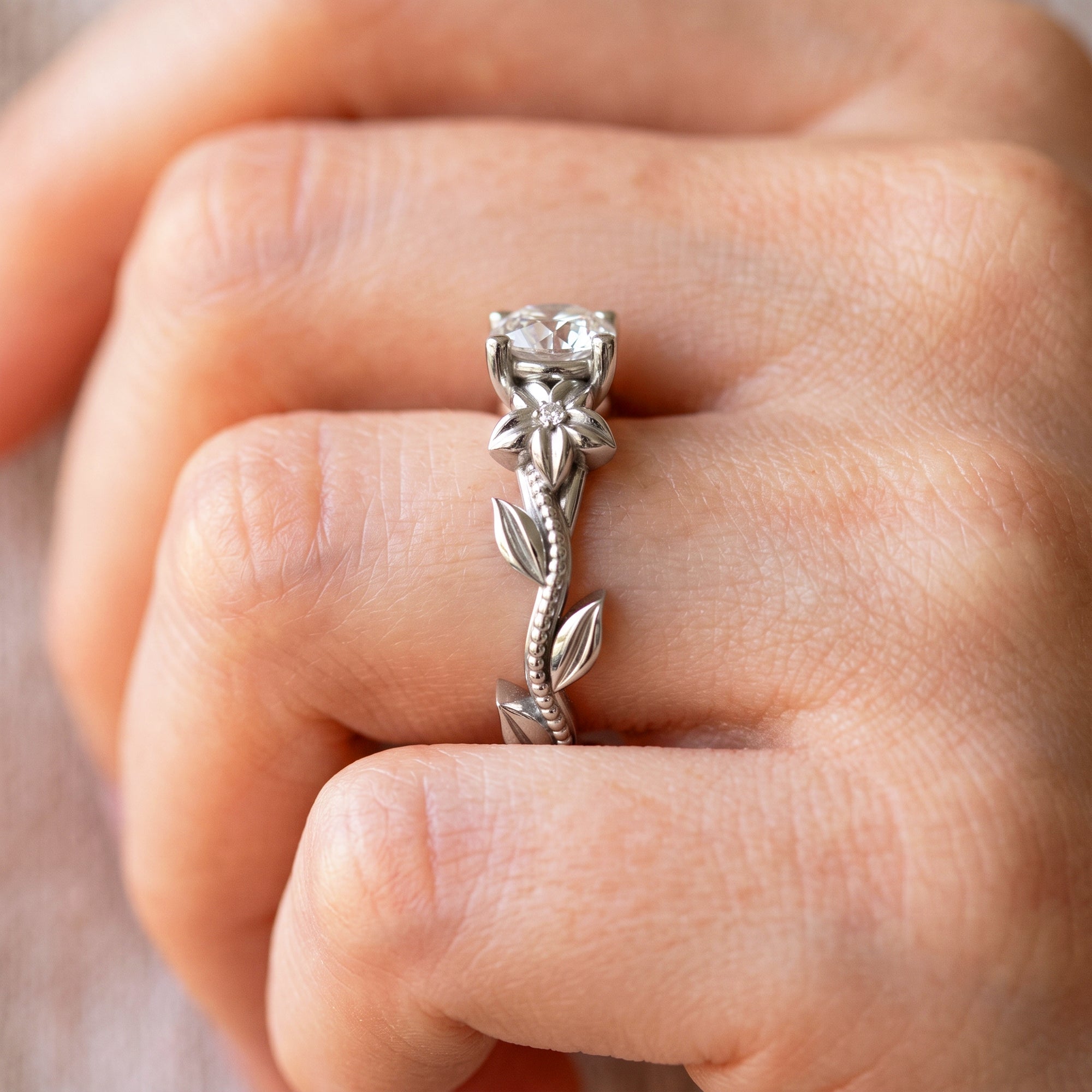 Nature inspired flower engagement ring shown on hand in 14k white gold